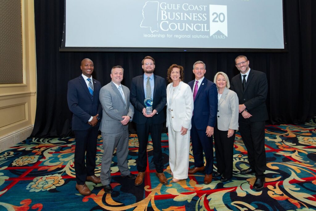 Seven people pose with the 2026 Rising Tide Award at the State of the Coast Symposium.