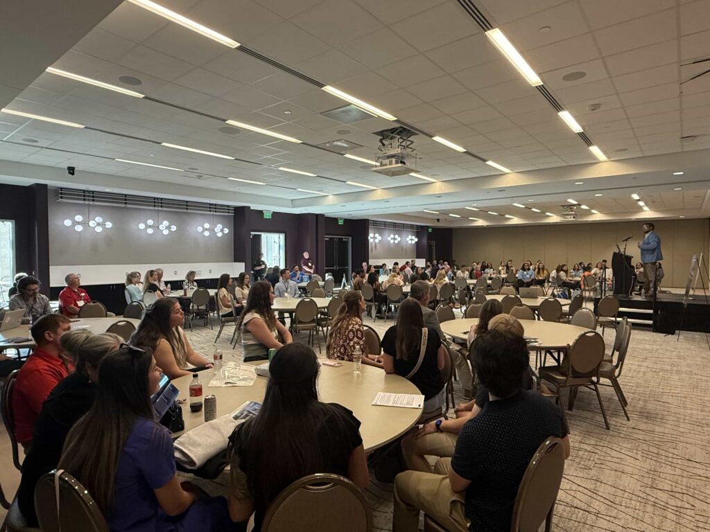 Dr. Kollin Napier addresses physical therapy professionals seated throughout the conference room.
