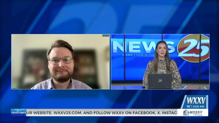 Dr. Kollin Napier appears by video beside WXXV News 25 anchor Megan Fayard during an interview about artificial intelligence safety.