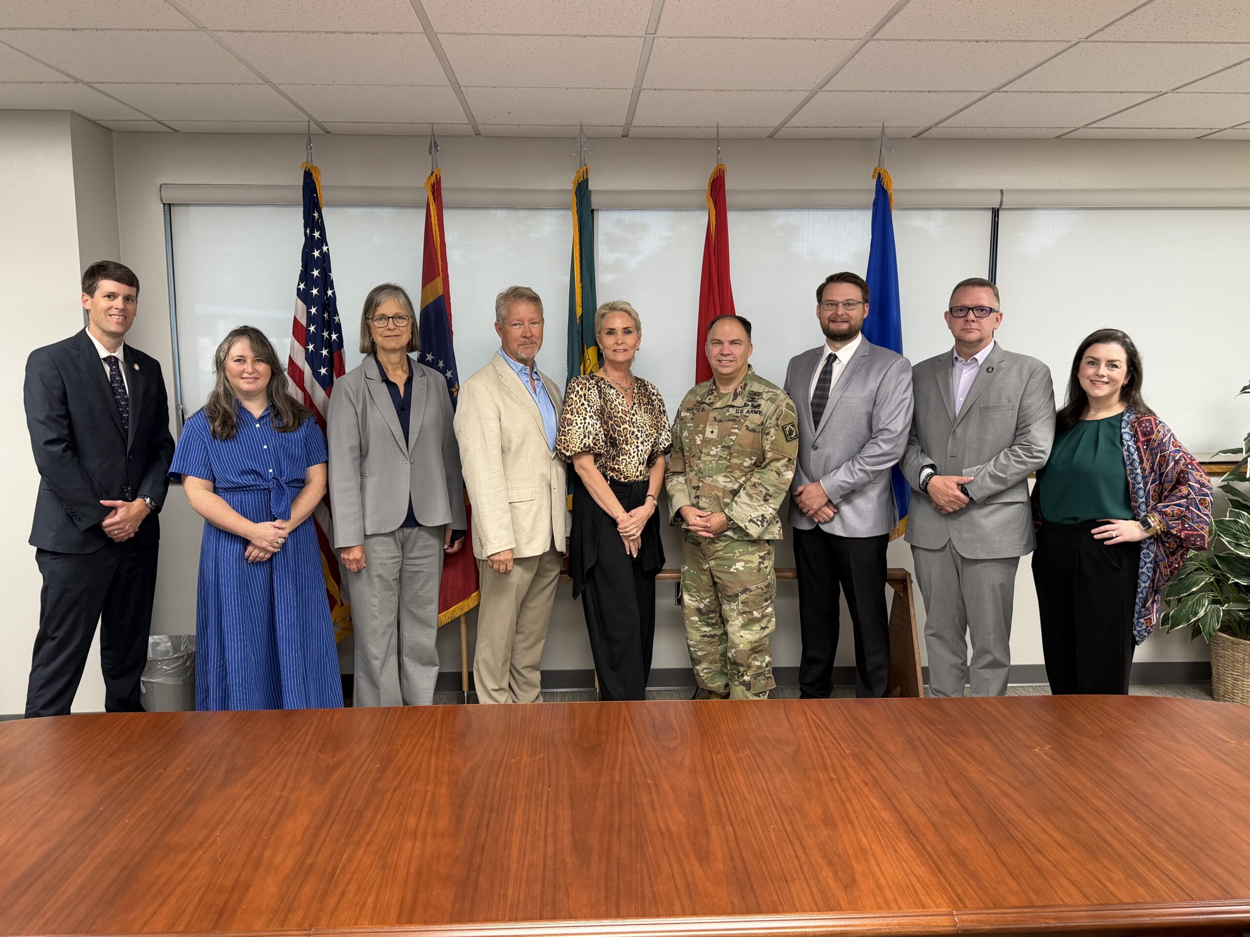 Task force members pose in front of military and state flags at Camp Shelby.
