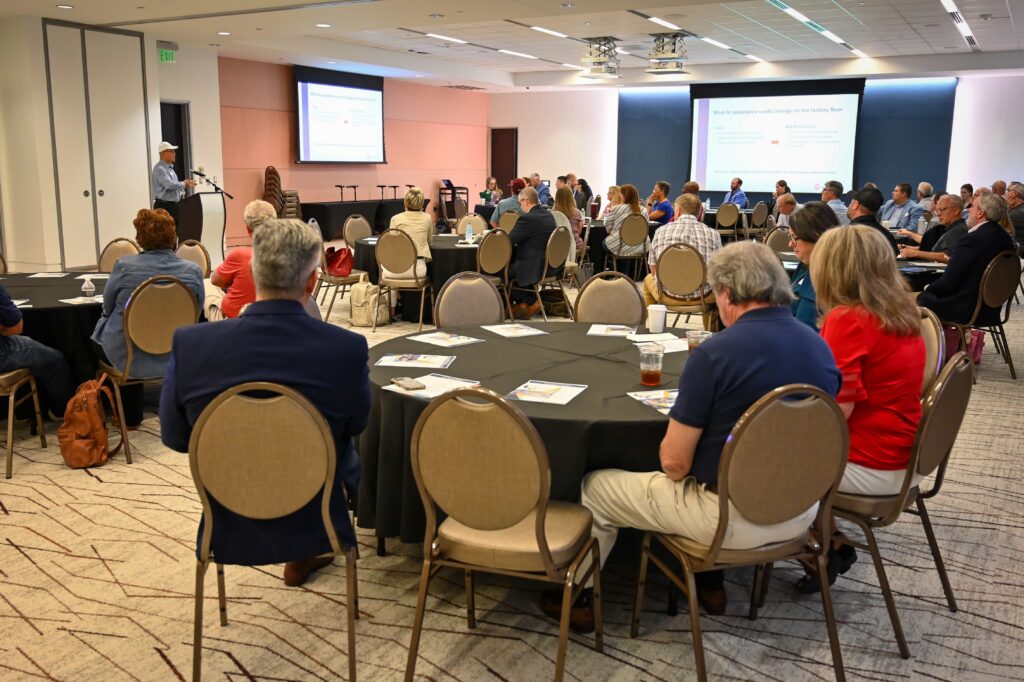 A presenter addresses AI in Manufacturing Day attendees seated at round tables at MGCCC.