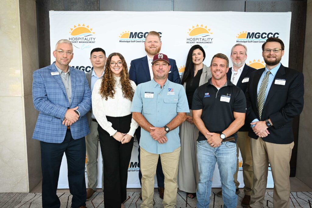 AI in Manufacturing Day presenters and panelists pose in front of an MGCCC backdrop.