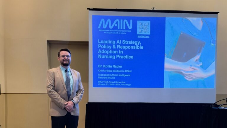 Dr. Kollin Napier stands beside a projection screen displaying the title of the nursing AI session.